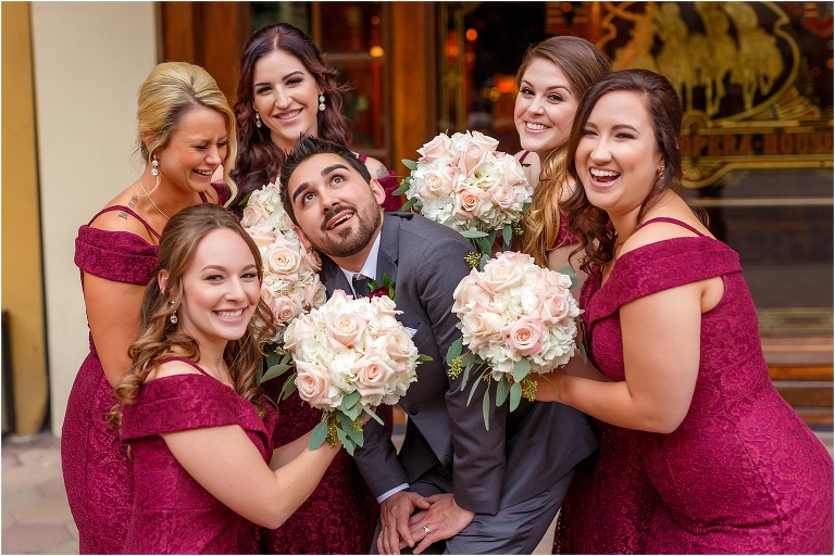 the bridesmaids laugh as they surround the groom's head with their Atmosphere Floral bouquets for a silly picture