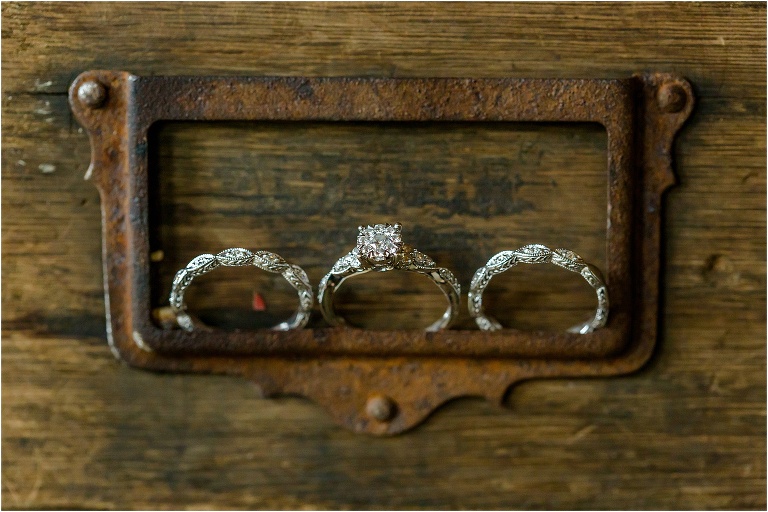 The bride's intricate engagement ring and wedding bands rest on an antique drawer