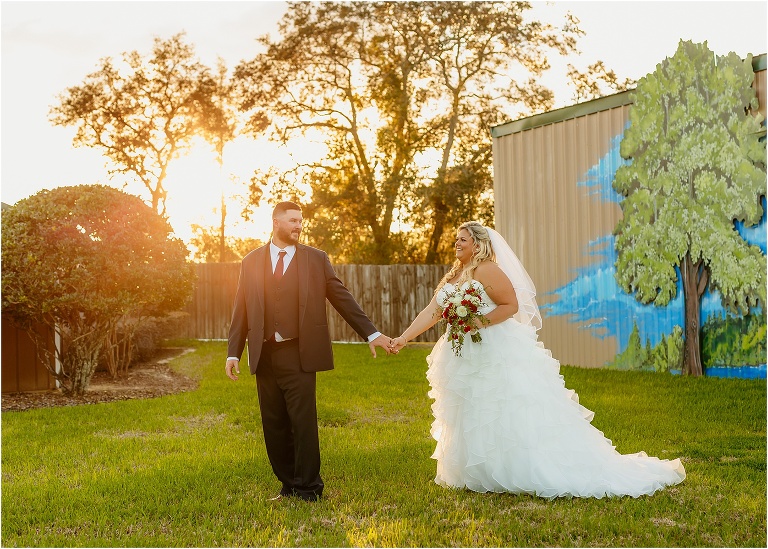 the bride and groom walk hand in hand as the sun dips below the horizon at Hidden Barn Venue