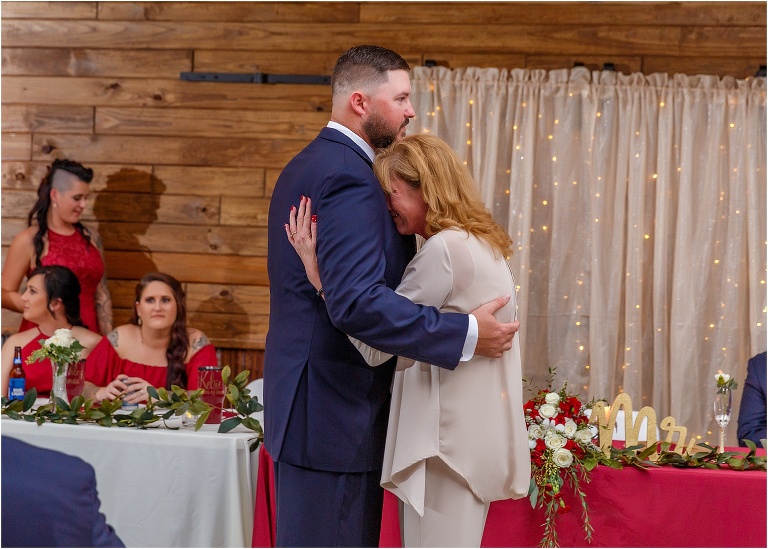 the mother of the groom cries into her son's chest as they share their mother & son dance at their Hidden Barn Venue wedding reception