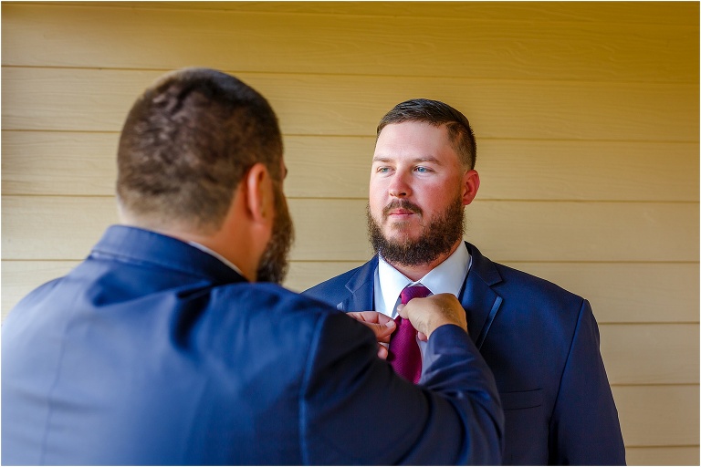 the best man adjusts the groom's tie as he prepares for his Hidden Barn Venue ceremony