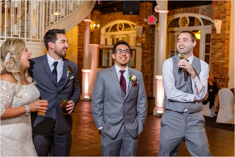 the bride and groom laugh hysterically as the best man makes his toast to the couple at their Orchid Garden at Church Street Station wedding reception