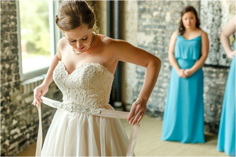 the bride places her En Vogue bridal belt around her waist for the finishing touch at Oxford Exchange