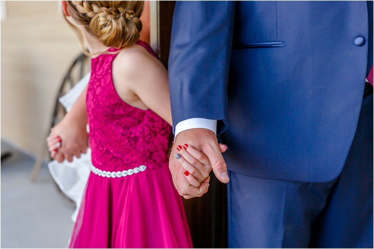 the bride and groom each hold their daughter's hands before their Hidden Barn Venue ceremony