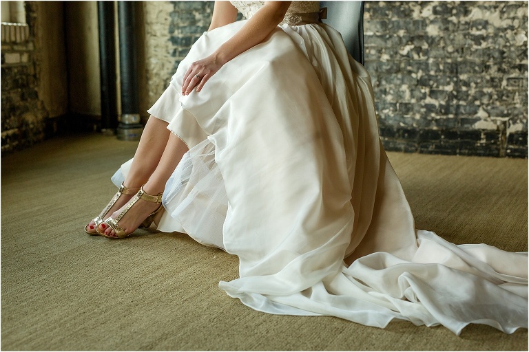 The bride's Kenneth Cole shoes peak out from her Essense of Australia wedding gown in the getting ready room at Oxford Exchange