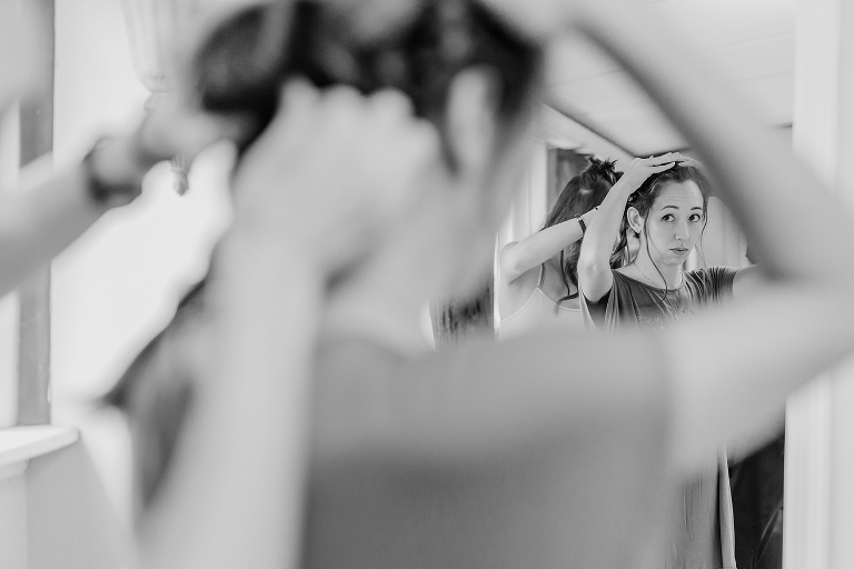 a peek through the bride's arm as she looks in the mirror getting her hair done before her Harmony Gardens wedding