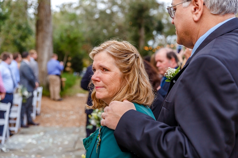 the mother of the groom sheds a tear as she watches her son at the altar 