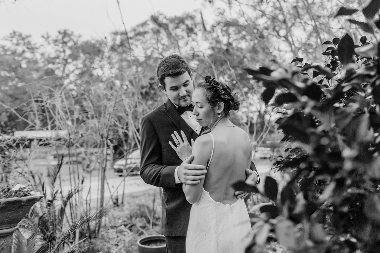 the bride looks over her shoulder as her groom looks down at her and wraps her in his arms