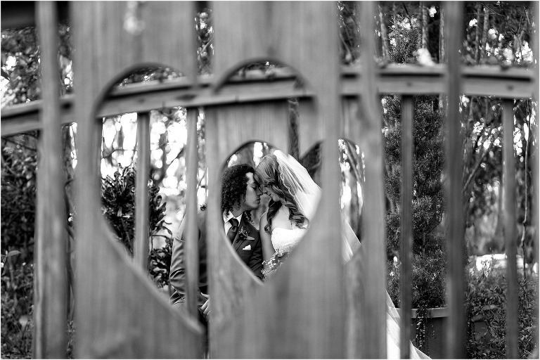 bride & groom touch foreheads as seen through the carved out heart shape in the bridge