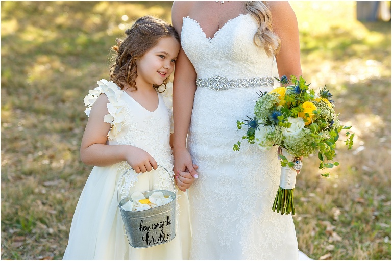 the flower girl snuggles up against the bride before the Cottom Farm wedding ceremony
