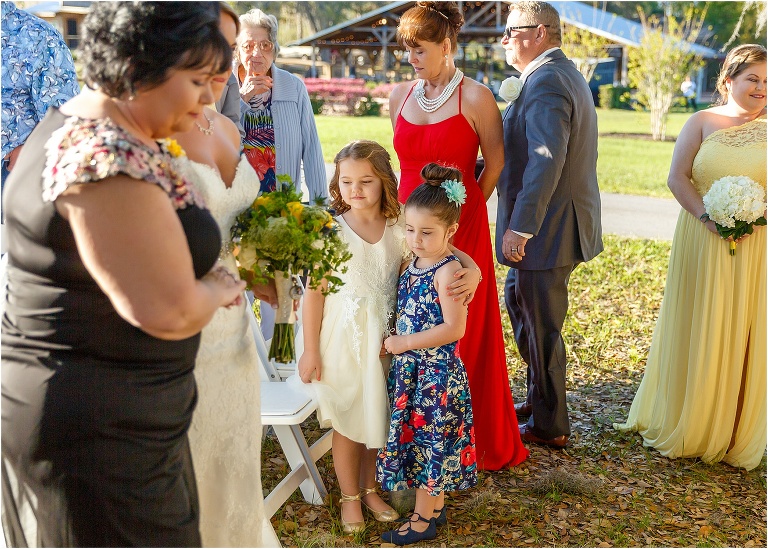 the bride's nieces hug each other as they watch their aunt walk down the aisle at her Cottom Farm wedding ceremony