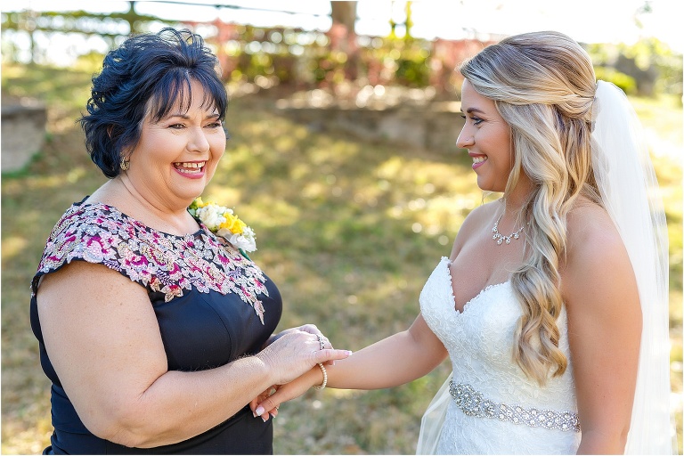 the mother of the bride giggles as she helps put on her daughter's bracelet before her Cottom Farm wedding