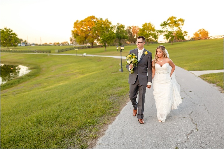 the bride & groom walk hand in hand around the lake at their Cottom Farm wedding