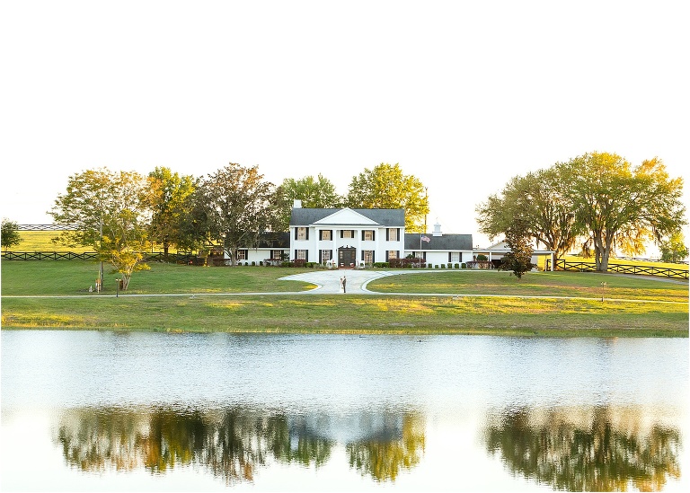 the house and trees reflected in the lake at their Cottom Farm wedding