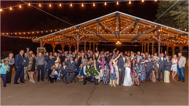 the bride & groom kiss under the market lights as all of their guests cheer around them at their Cottom Farm wedding