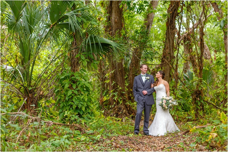 the bride & groom walk arm in arm through the towering trees at their Bakers Ranch wedding