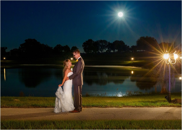 the moon shines brightly over the lake as the bride & groom look lovingly at each other at the end of their Cottom Farm wedding
