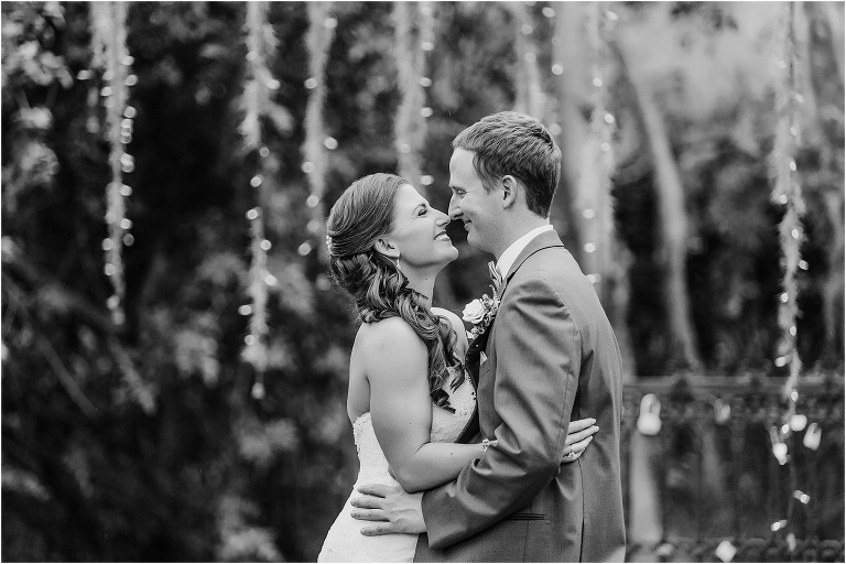 the bride and groom nuzzle noses as the twinkle lights glow behind them at their Bakers Ranch wedding
