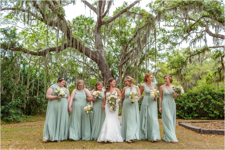 the bride laughs and walks with her bridesmaids in their mint green bridesmaid dresses