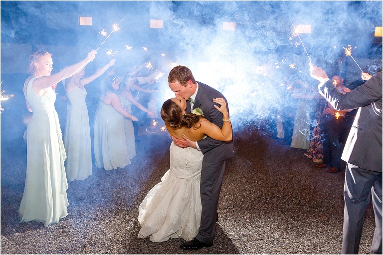 the bride and groom kiss under the sparklers during their grand exit from their Bakers Ranch wedding