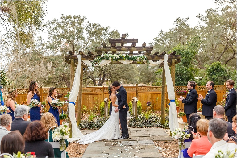 bride & groom kiss under their ceremony arch at their Harmony Gardens wedding