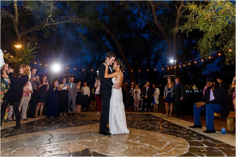 bride & groom share their first dance under the market lights surrounded by their family and friends