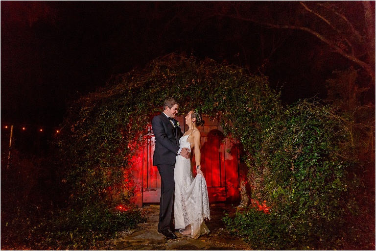 the groom dips his bride in front of the vine covered Hobbit door at Harmony Gardens wedding venue