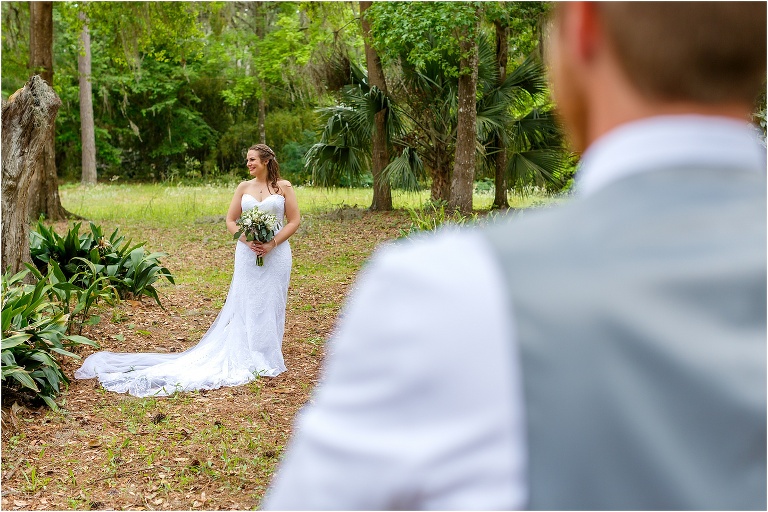 the groom looks on as his stunning bride has her photo taken before their Bellemoor Plantation wedding