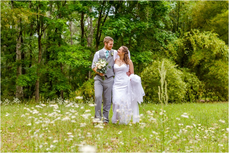 the bride & groom take a stroll through the wildflowers at their Bellemoor Plantation wedding