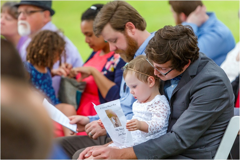 the flower girl reads the program in her dad's lap