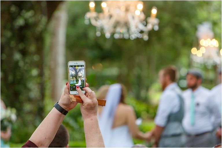 a guest snaps a photo on her phone during their Bellemoor plantation wedding ceremony