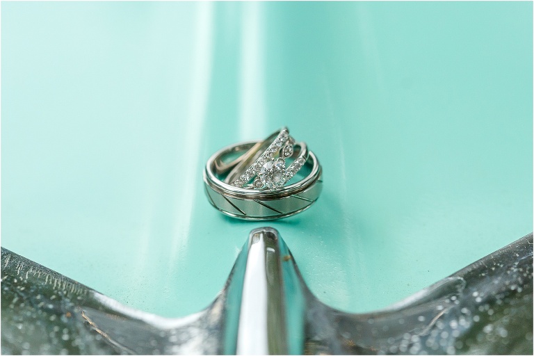 the couples intricate wedding rings sit atop a mint green Bel Air. 