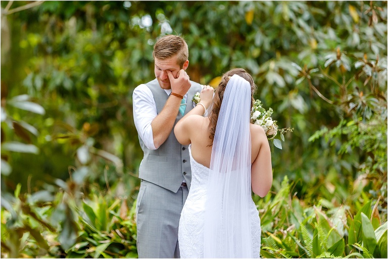 the groom wipes his tears away as his bride cleans a spot off his shirt during their first look