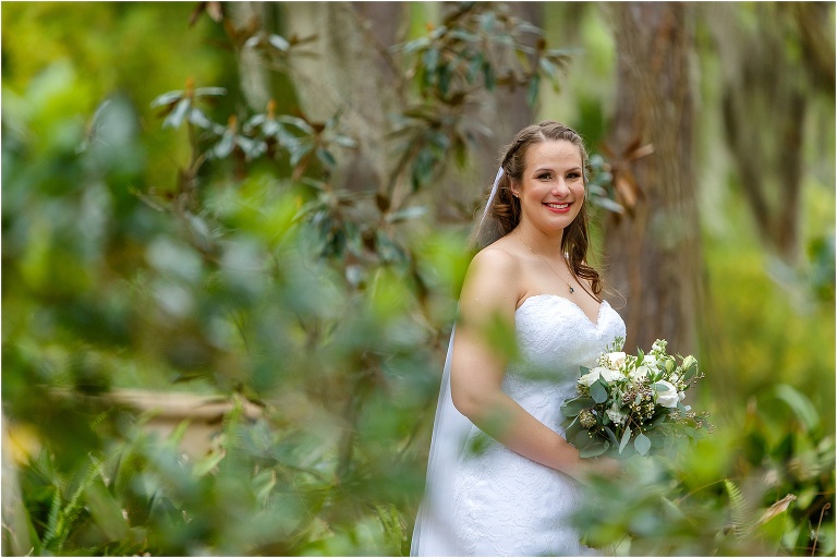 a peak through the greenery at the gorgeous bride in her Maggie Sottero wedding dress