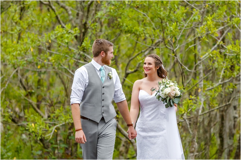 the bride smiles at her groom as he leads her down the dock at their Bellemoor Plantation wedding
