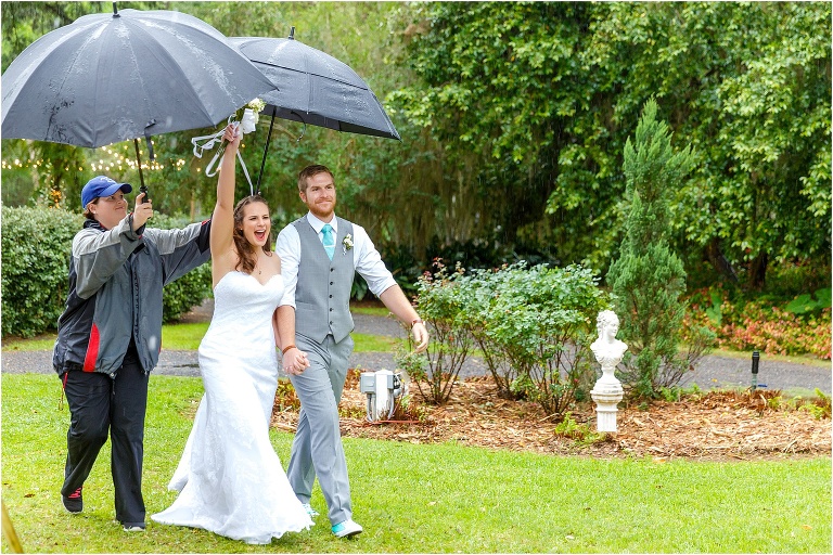 the bride and groom enter their reception while a Bellemoor Plantation employee holds umbrellas above them