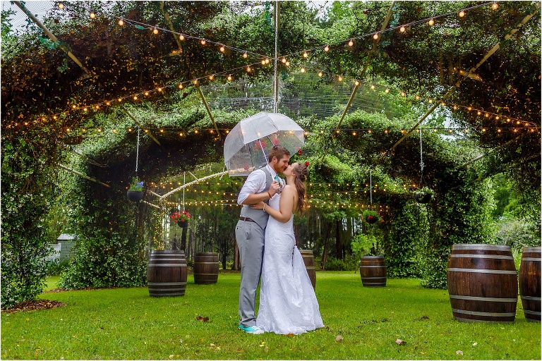 the bride & groom share a kiss under an umbrella during their Bellemoor Plantation wedding