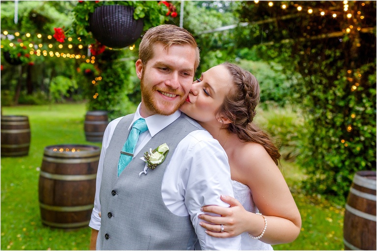 the bride kisses her groom on the cheek under the market lights at their Bellemoor Plantation wedding