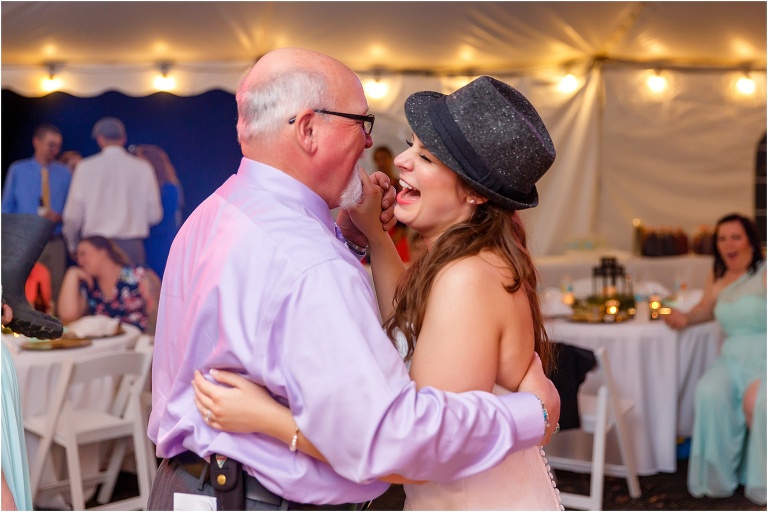 the bride laughs as she shares a dance with the groom's father during their dollar dance