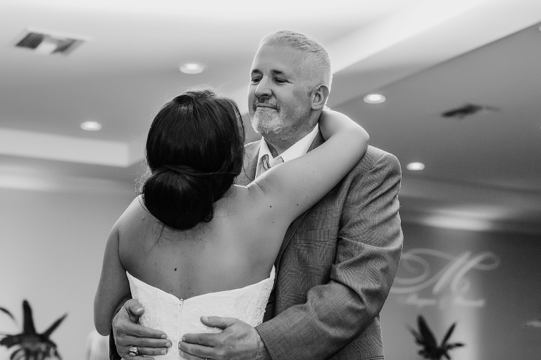 the father of the bride looks lovingly down at his daughter during their dance together