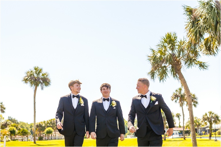 the groom & his groomsmen stroll among the tall palm trees before the crystal river wedding