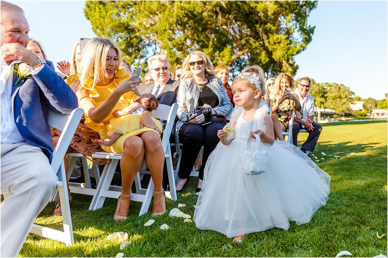 guests laugh as the flower girl makes her way down the aisle 