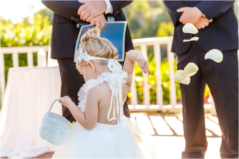 the flower girl tosses rose petals over her shoulder as she gets to the end of the aisle at their crystal river wedding