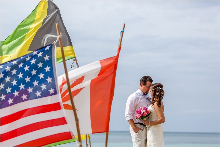 the bride and groom take a moment forehead to forehead next to the flags blowing in the wind