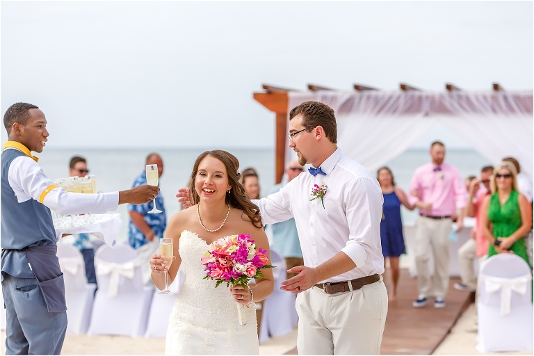a server hands the bride and groom glasses of champagne after they said "I do" at their Montego Bay wedding