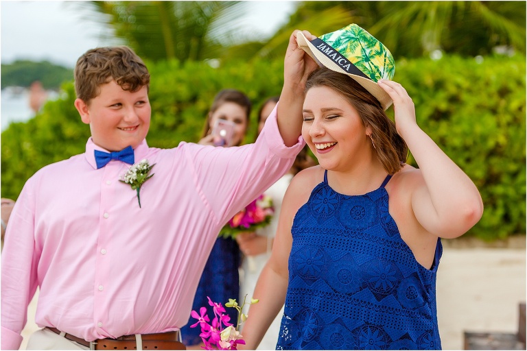 a groomsman shares his Jamaica hat with one of the bridemaids
