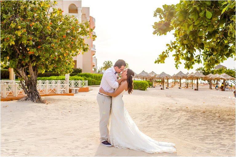 the groom pulls his bride in to kiss her as the sun starts to set behind them after their Montego Bay wedding