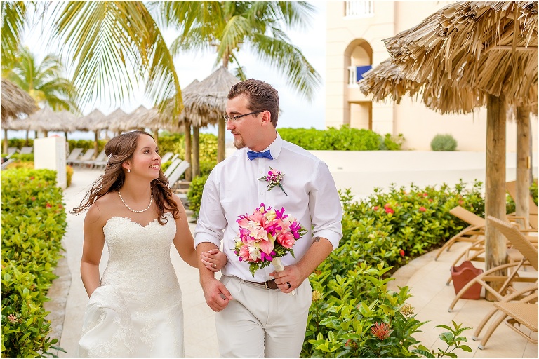 the bride and groom lock eyes as they walk arm in arm around the Rose Hall Suites resort