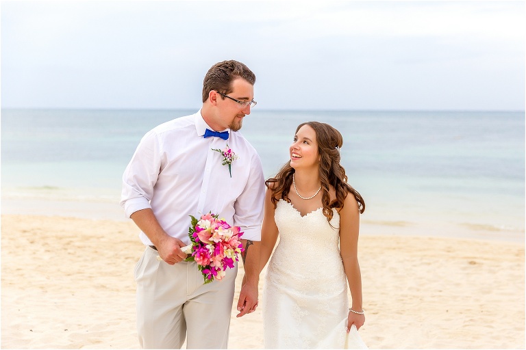 groom carries the bride's pink bouquet at their destination wedding in Jamaica