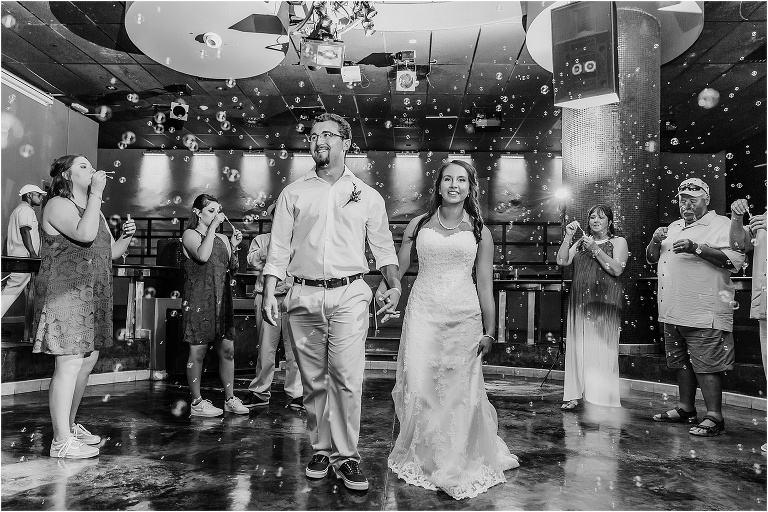 the bride and groom smile as they walk hand in hand through the bubbles their guests are blowing as they exit their Montego Bay wedding reception